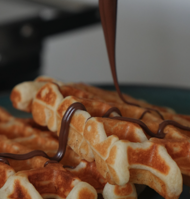 Waffeln mit geschmolzener Schokolade, auf einem Teller angerichtet.