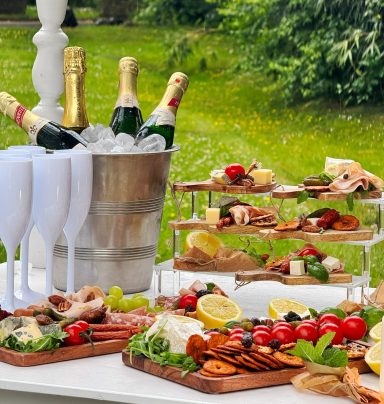 Ein gedeckter Tisch mit Essen Ein gedeckter Tisch mit Essen und Sektflaschen in einem Garten.