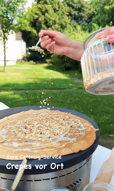 Pfannkuchen wird mit Nüssen und Pudding belegt, im Freien zubereitet.